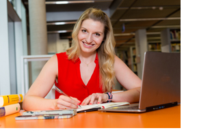 Frau sitzt vor ihrem Laptop und macht sich Notizen in einem Buch. (Foto: Karsten Socher) 