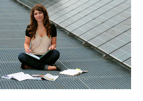 Eine Studentin sitzt neben Solaranlagen und lernt. (Foto: Christof Stache)